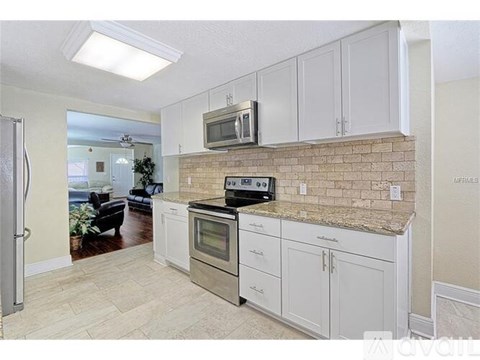 A kitchen with white cabinets and a brick backsplash.