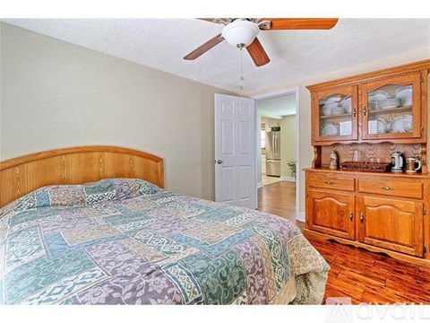 A bedroom with a bed, dresser, and a ceiling fan.