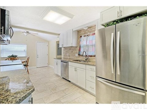 A kitchen with a refrigerator, cabinets, and a countertop.