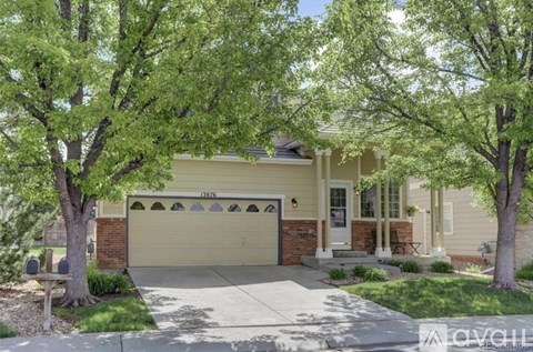 A house with a garage and a driveway is surrounded by trees.