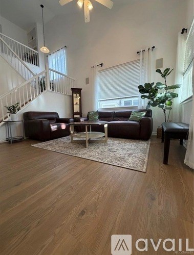 A living room with a brown leather couch and a wooden floor.