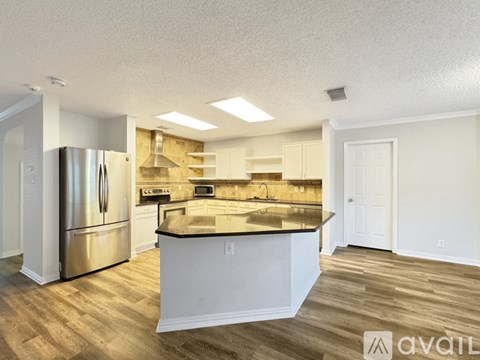 A kitchen with a stainless steel refrigerator and wooden flooring.