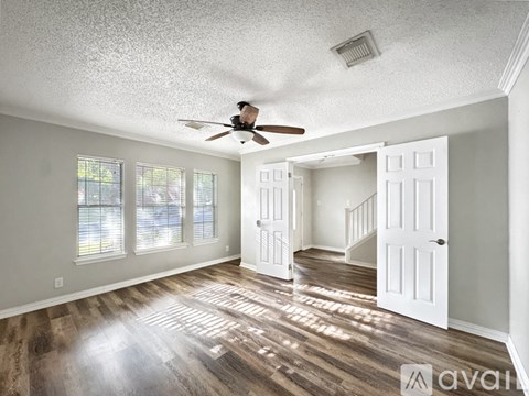 A spacious room with a ceiling fan and wooden flooring.
