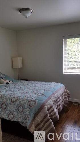 A bedroom with a bed and a window with blinds.