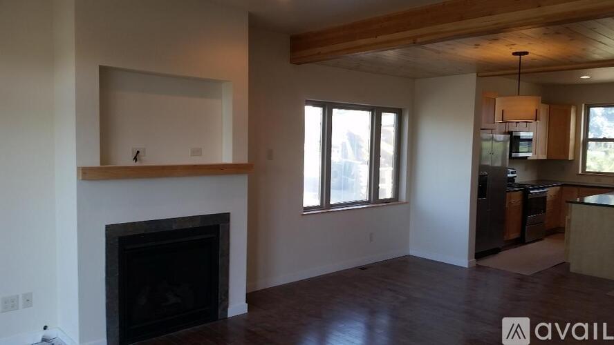 A living room with a fireplace and a kitchen area in the background.