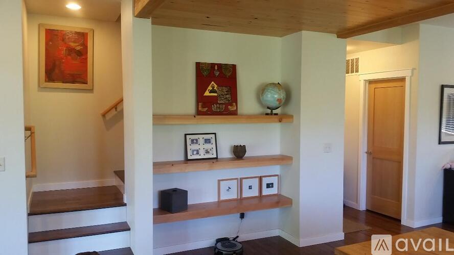 A hallway with a wooden staircase and a shelf with various objects on it.