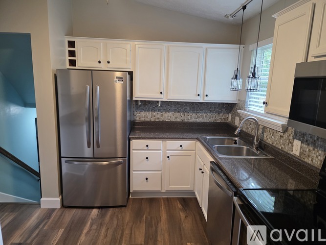 A kitchen with a stainless steel refrigerator and white cabinets.