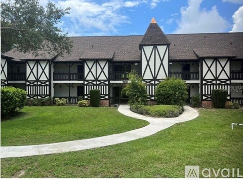 A building with a black and white facade has a grassy area in front of it.