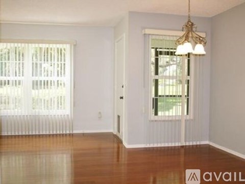 A room with wooden floors and a window with blinds.