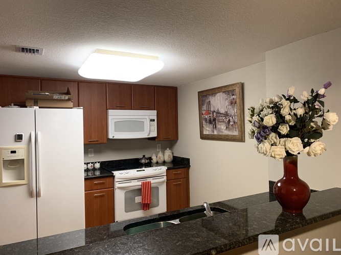 A kitchen with a refrigerator, microwave, oven, and a vase of flowers.