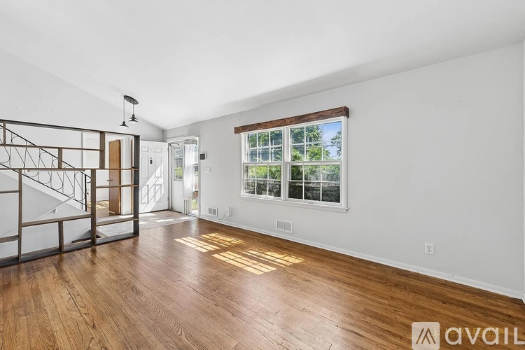 A room with wooden floors and a window showing trees outside.