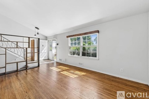 A room with wooden floors and a window showing trees outside.