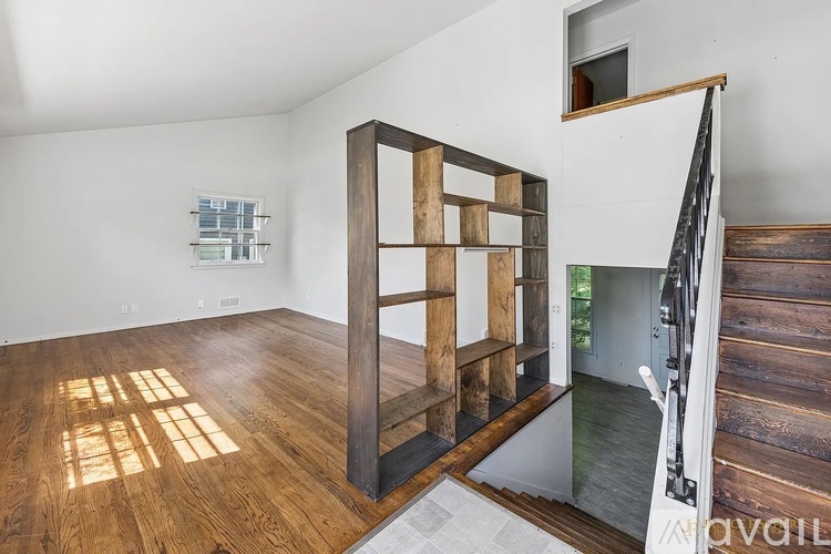 A wooden staircase with a glass railing leads to another room.
