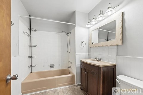 A bathroom with a tub, sink, and mirror.