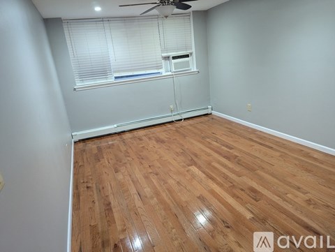 A room with wooden flooring and a window with blinds.