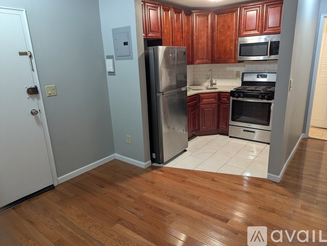 A kitchen with wooden cabinets and a stainless steel refrigerator.