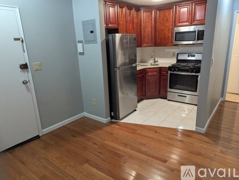 A kitchen with wooden cabinets and a stainless steel refrigerator.