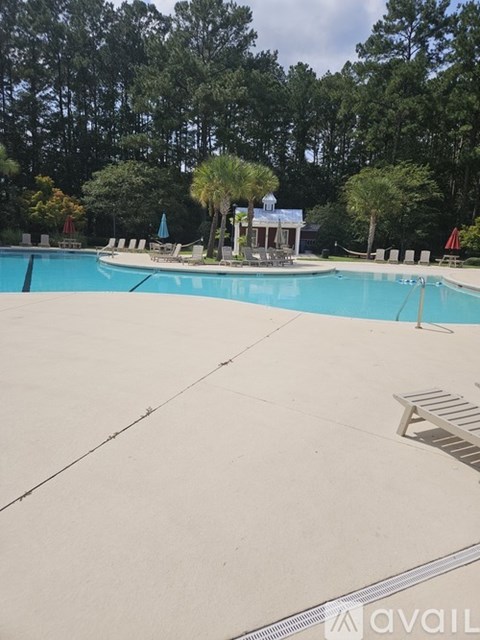 A large swimming pool surrounded by trees and a small building.