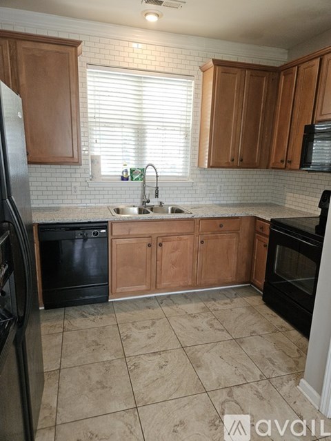 A kitchen with wooden cabinets and black appliances.