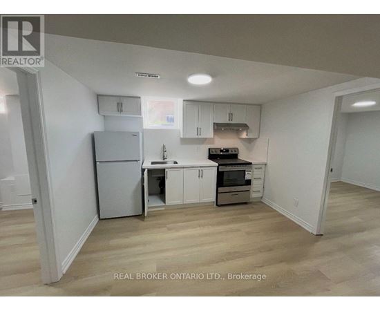 A kitchen with white cabinets and a refrigerator.