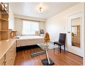 A bedroom with a bed, a chair, and a table with a vase of flowers on it.