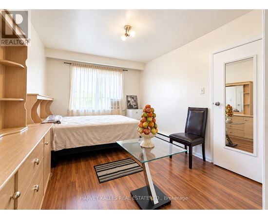 A bedroom with a bed, a chair, and a table with a vase of flowers on it.