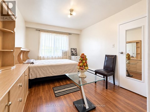 A bedroom with a bed, a chair, and a table with a vase of flowers on it.