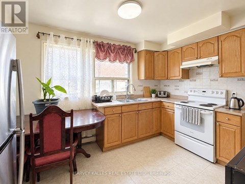 A kitchen with wooden cabinets and a red chair.