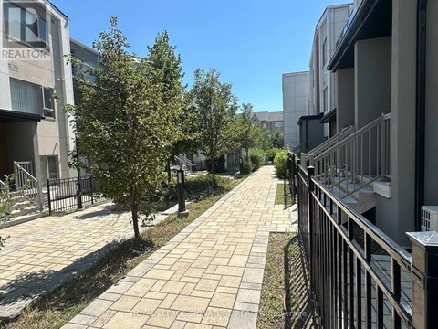 A sunny day in a residential area with apartment buildings on both sides of a paved walkway.