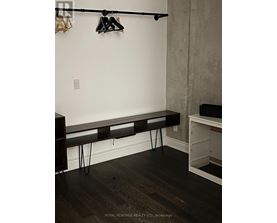 A black bench with hairpin legs sits in a corner of a room.