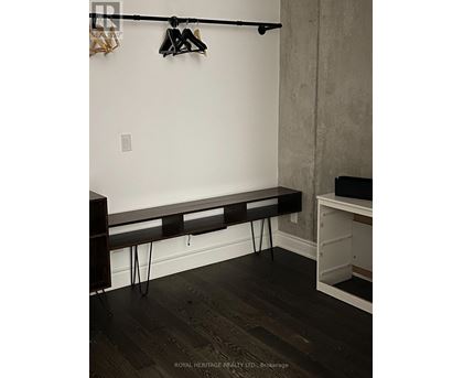 A black bench with hairpin legs sits in a corner of a room.