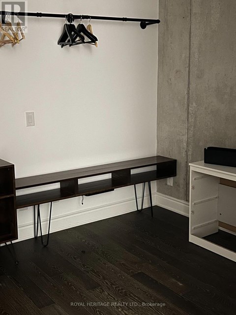 A black bench with hairpin legs sits in a corner of a room.