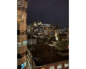 A cityscape at night with a building in the foreground that has a sign that says "Royal Heritage Realty Ltd.".