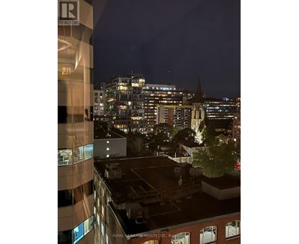 A cityscape at night with a building in the foreground that has a sign that says "Royal Heritage Realty Ltd.".