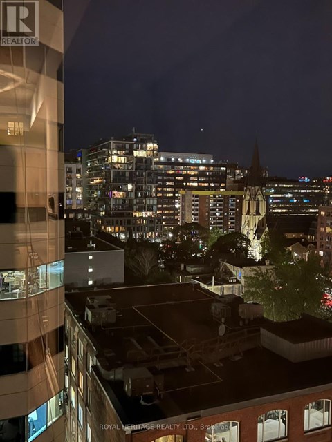 A cityscape at night with a building in the foreground that has a sign that says "Royal Heritage Realty Ltd.".