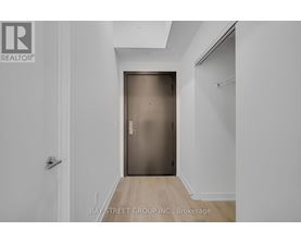 A white hallway with a wooden floor and a closed door.