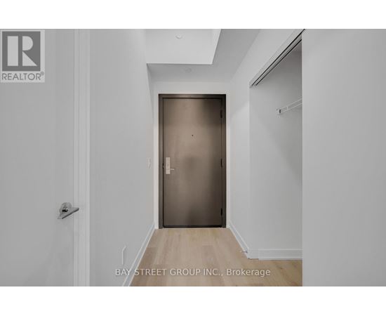 A white hallway with a wooden floor and a closed door.