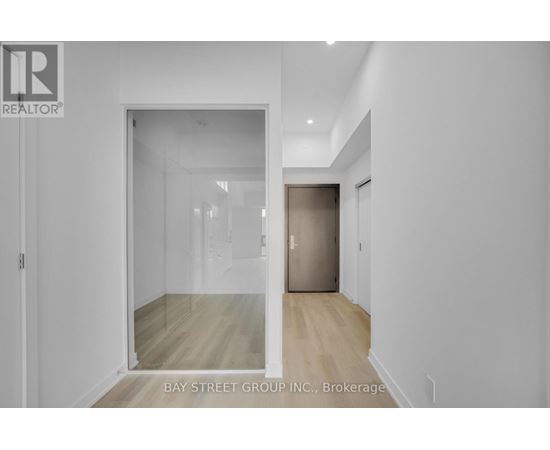 A white hallway with a glass door leading to another room.