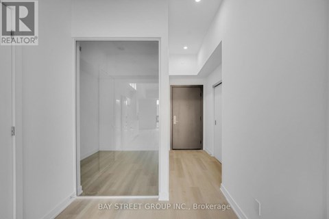 A white hallway with a glass door leading to another room.