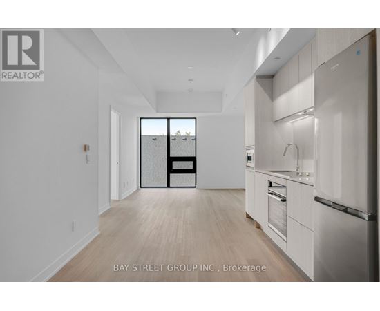 A spacious kitchen with white cabinets and a refrigerator.