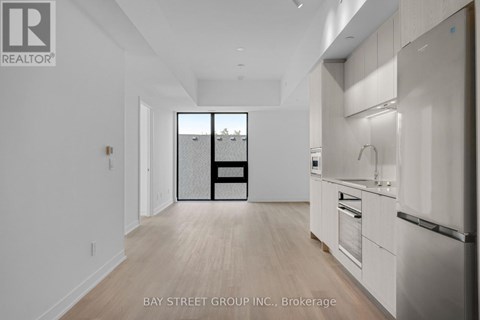 A spacious kitchen with white cabinets and a refrigerator.