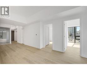 A spacious room with wooden flooring and white walls, with a view of a cityscape through a glass door.