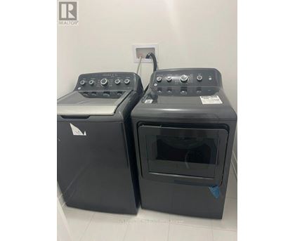 Two black ovens with control panels on top are in a white room.