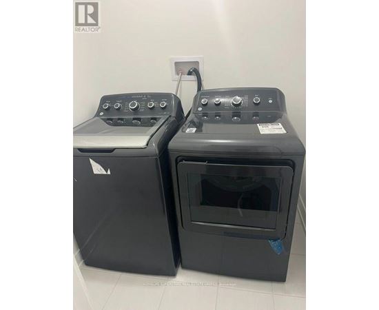 Two black ovens with control panels on top are in a white room.