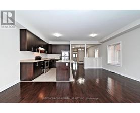 A spacious kitchen with dark wood floors and white walls.
