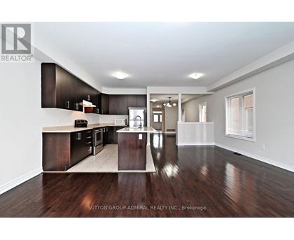 A spacious kitchen with dark wood floors and white walls.