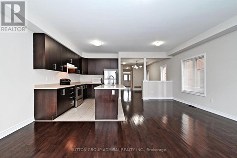 A spacious kitchen with dark wood floors and white walls.