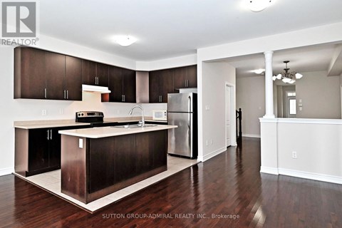 A kitchen with dark wood cabinets and a white island.