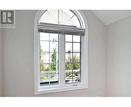 A white room with a large arched window that has a view of a balcony and trees.