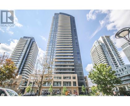 A tall building with a glass facade stands in the center of a city street.